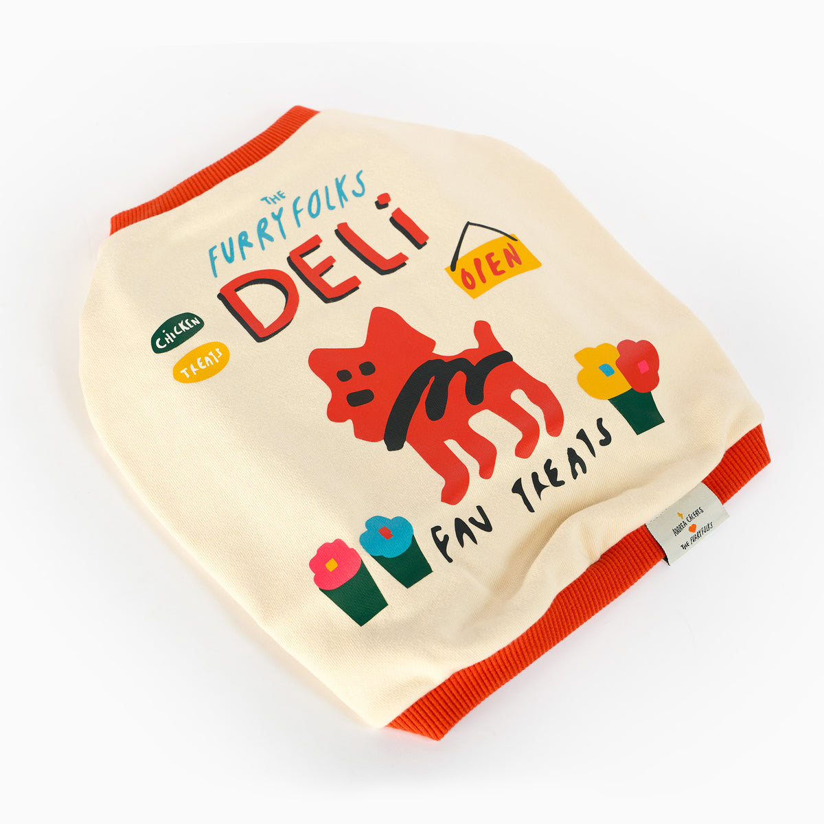Cream dog shirt laid flat on a white background, featuring orange ribbed trim, “the furryfolks deli” lettering, a red cartoon dog, colorful potted flowers, and a yellow “open” sign.