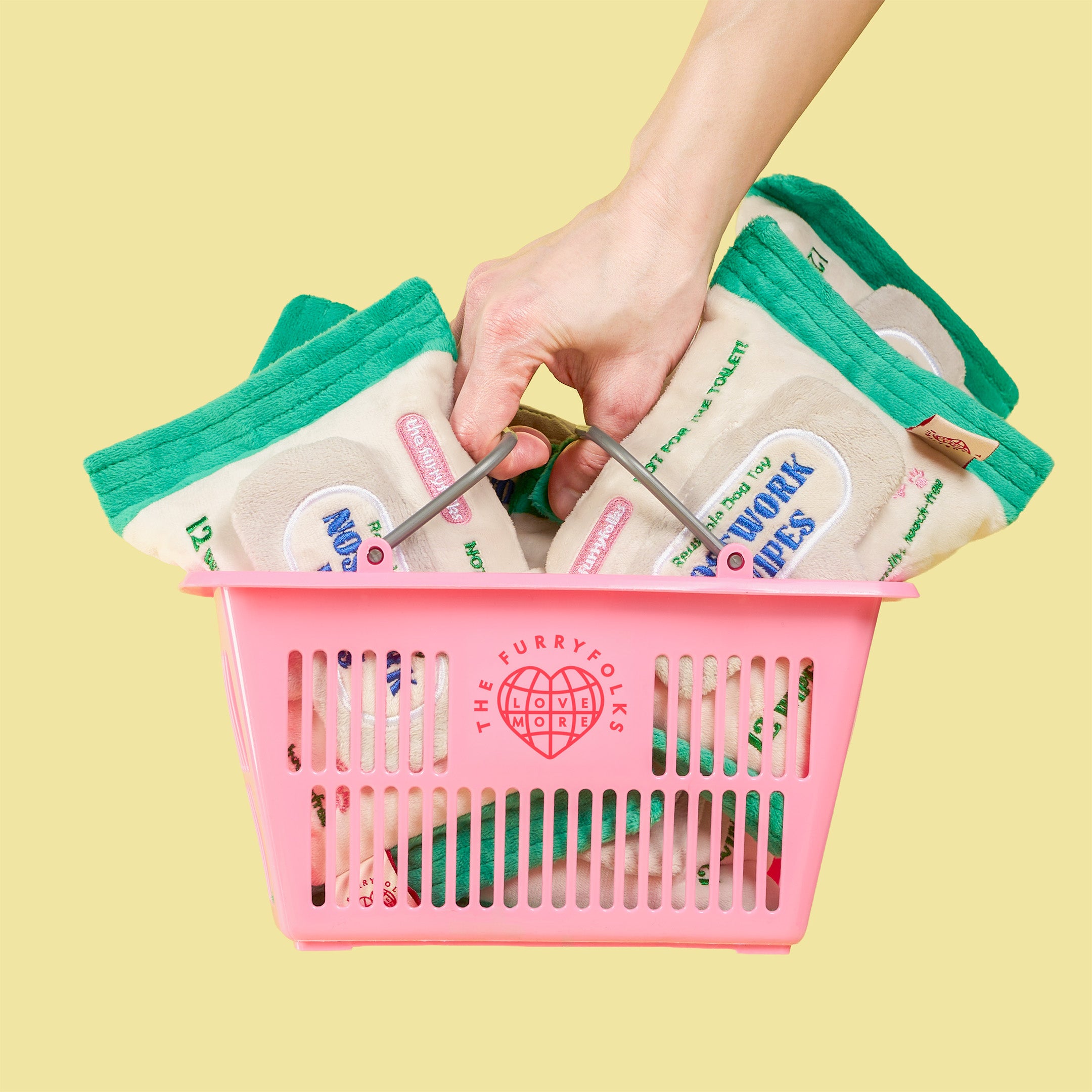 Hand holding a pink basket with packages labeled 'The Furry Polks' against a yellow background