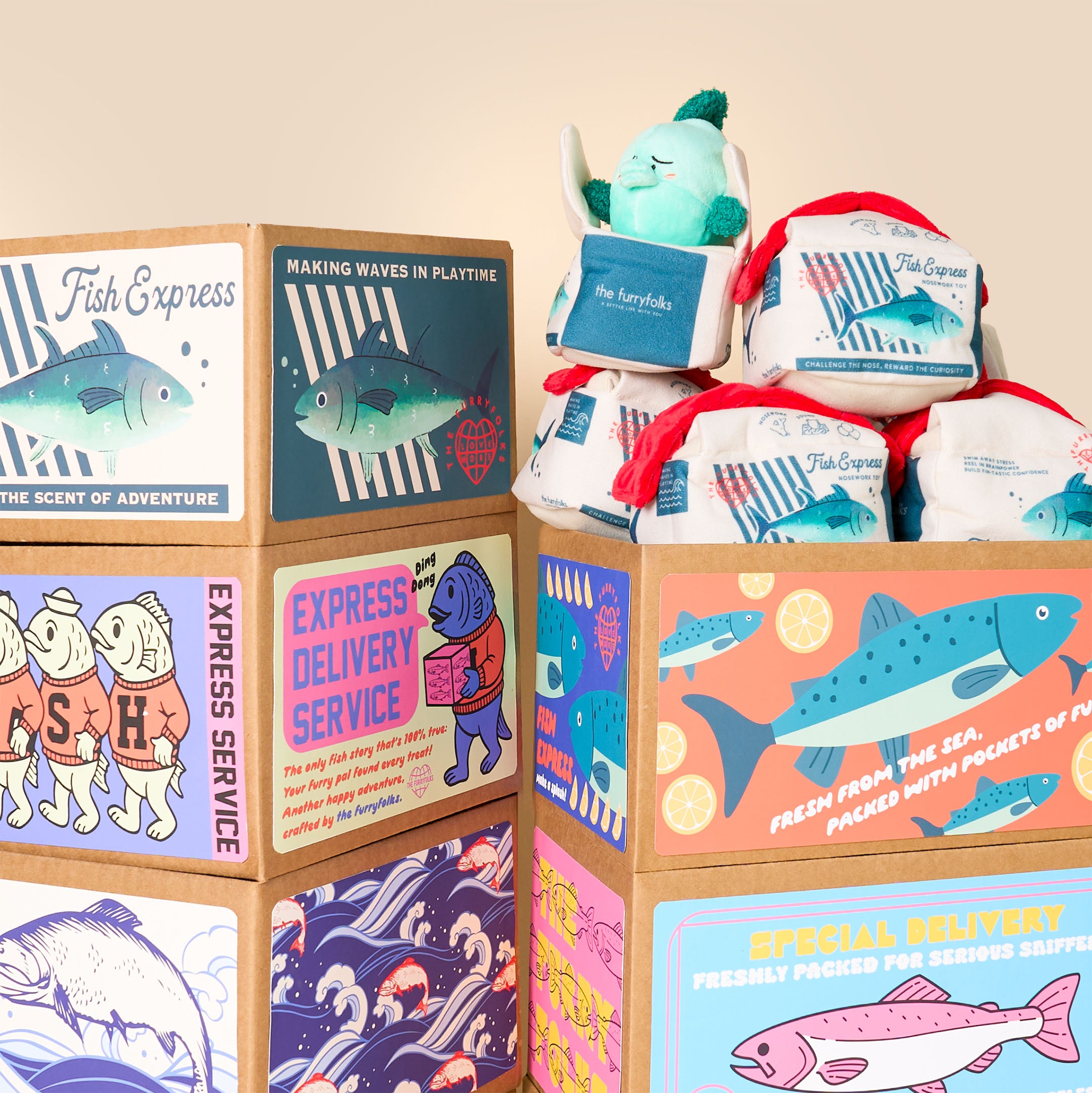 Stack of plush toys and boxes with fish-themed graphics on a beige background