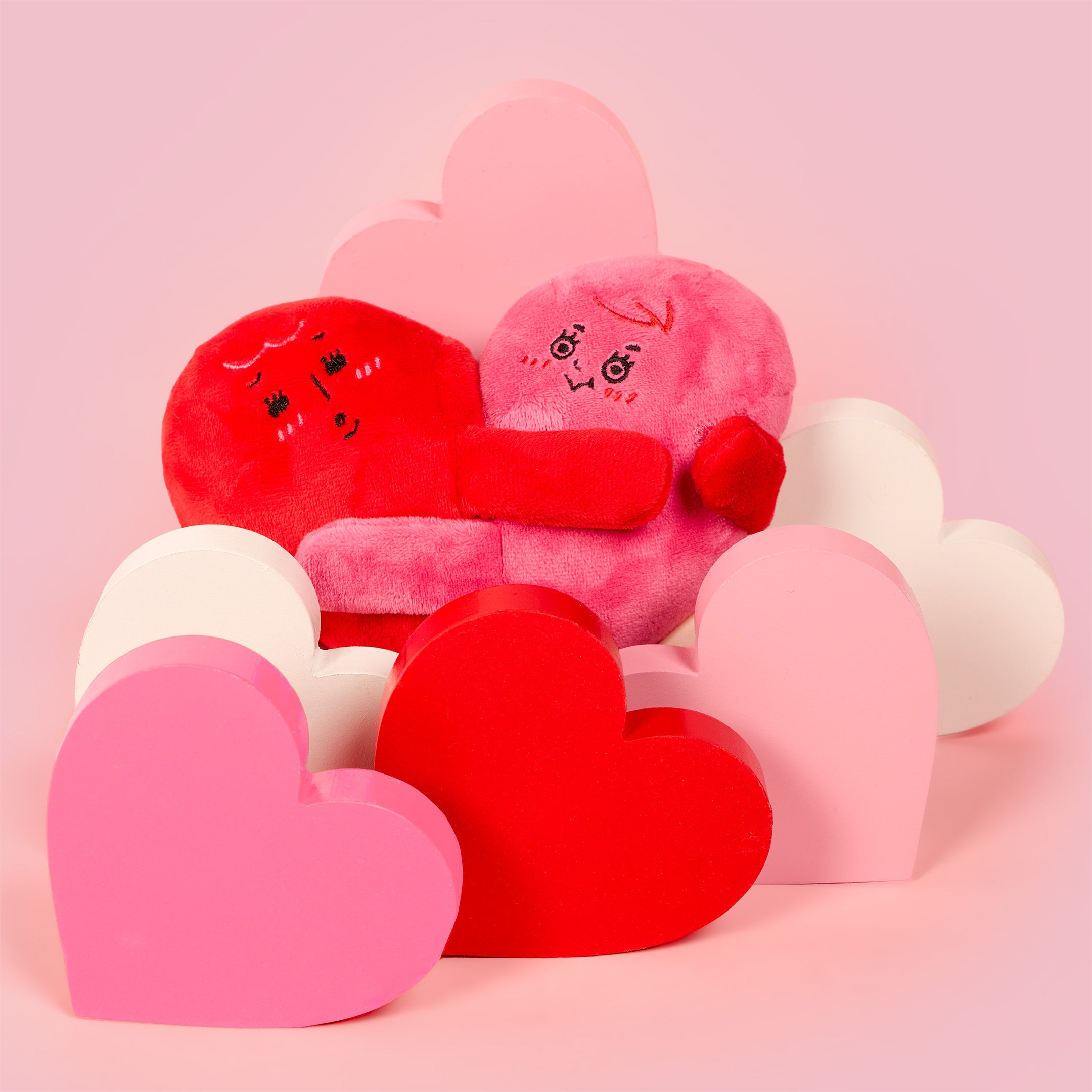 Heart-shaped plush toys on a pink background