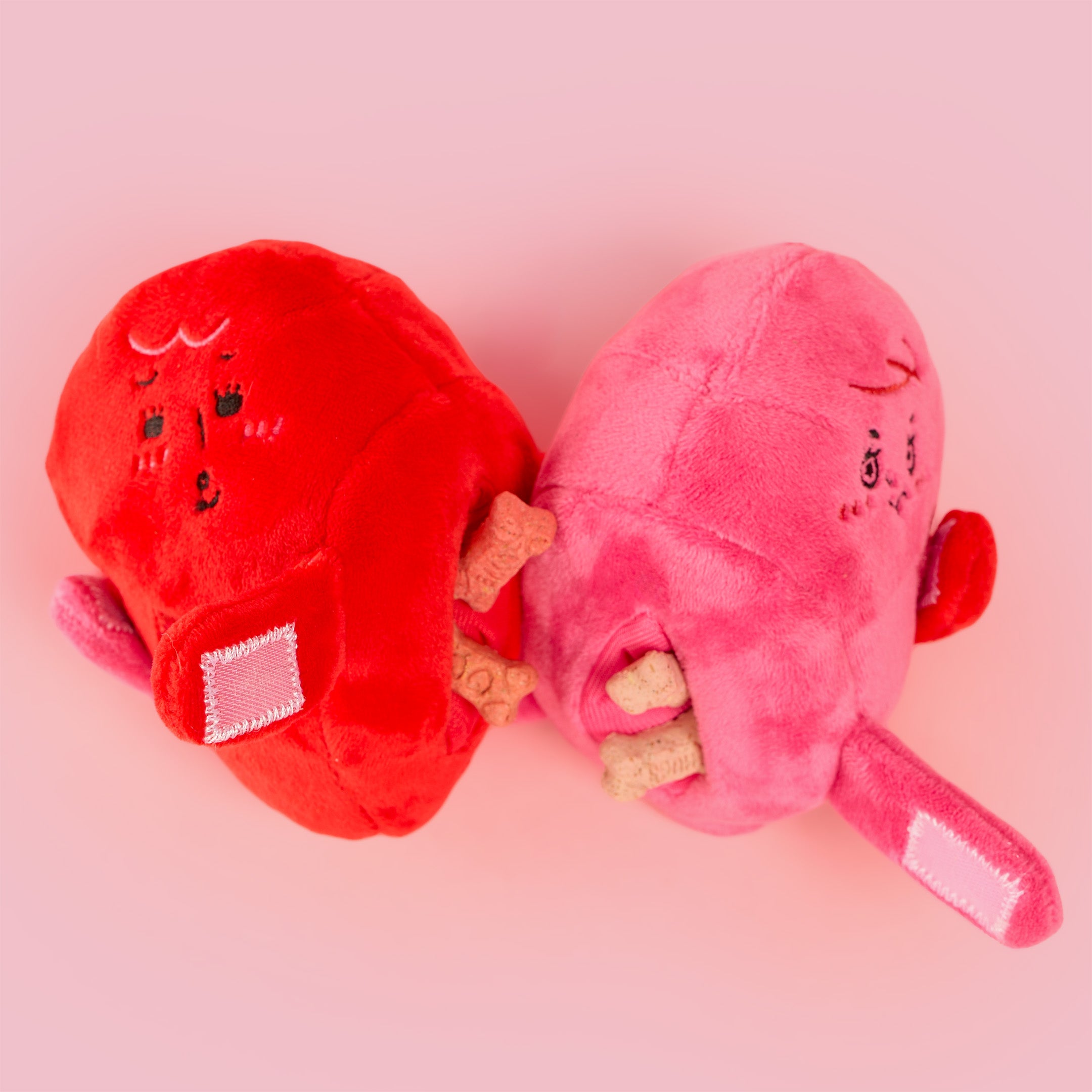 Red and pink plush slippers with cartoon faces on a pink background