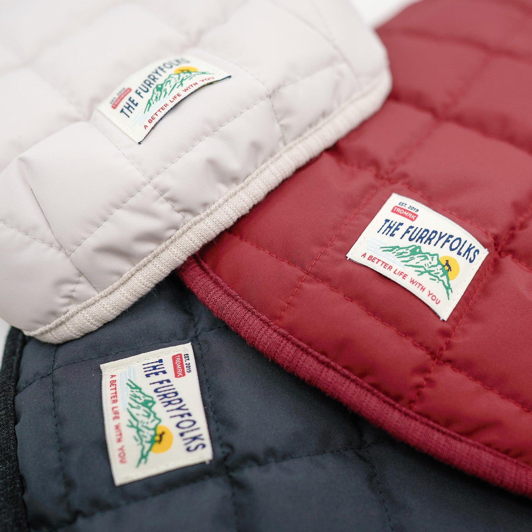 Three quilted pads in white, red, and navy with 'The furryfolks' labels.