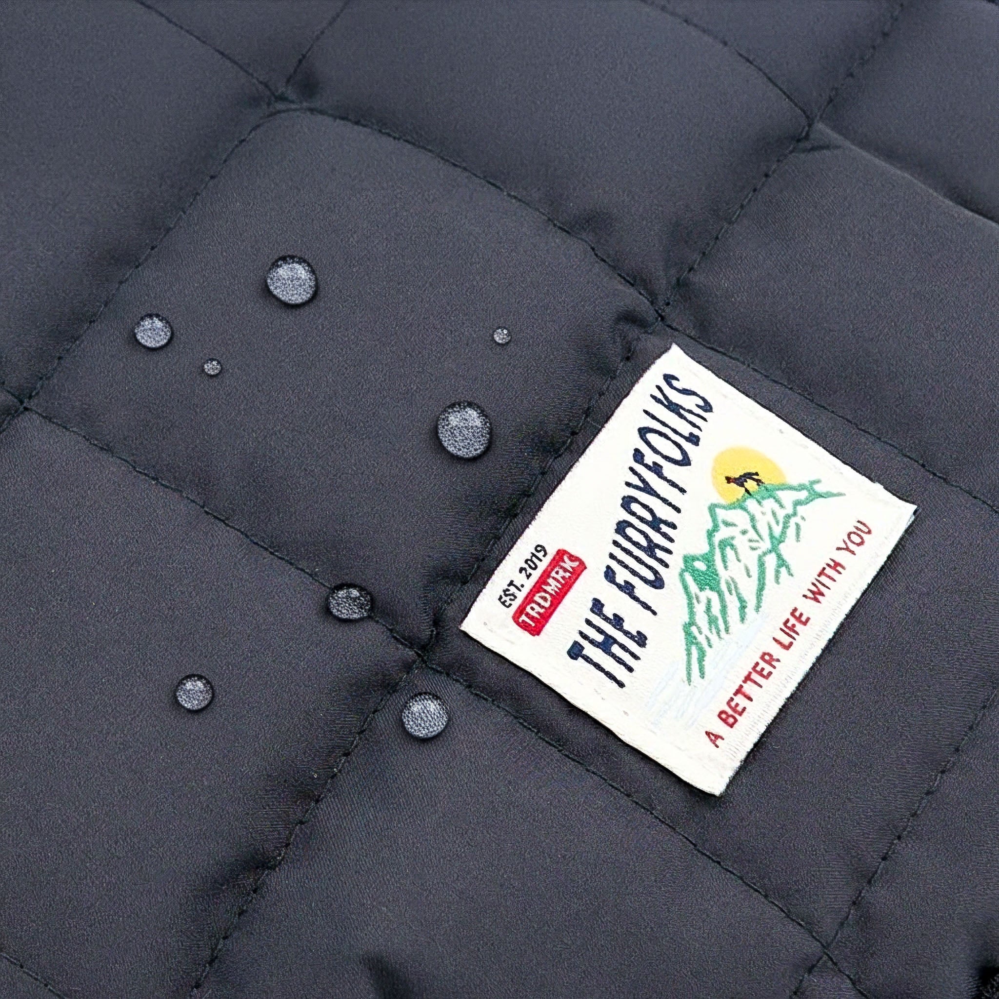 Close-up of a quilted jacket with a brand label on a dark gray background