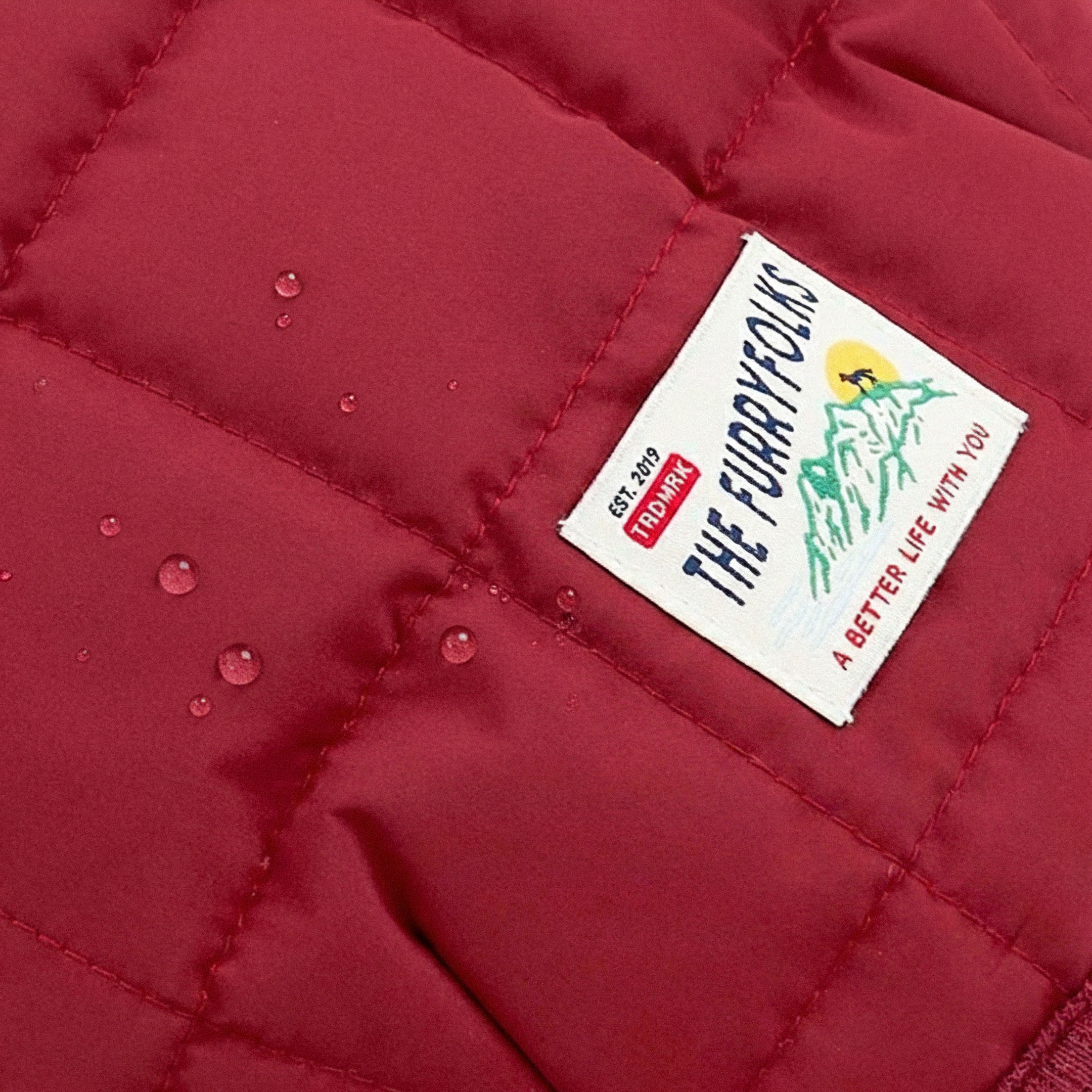 Close-up of a red quilted jacket with a brand label on it.
