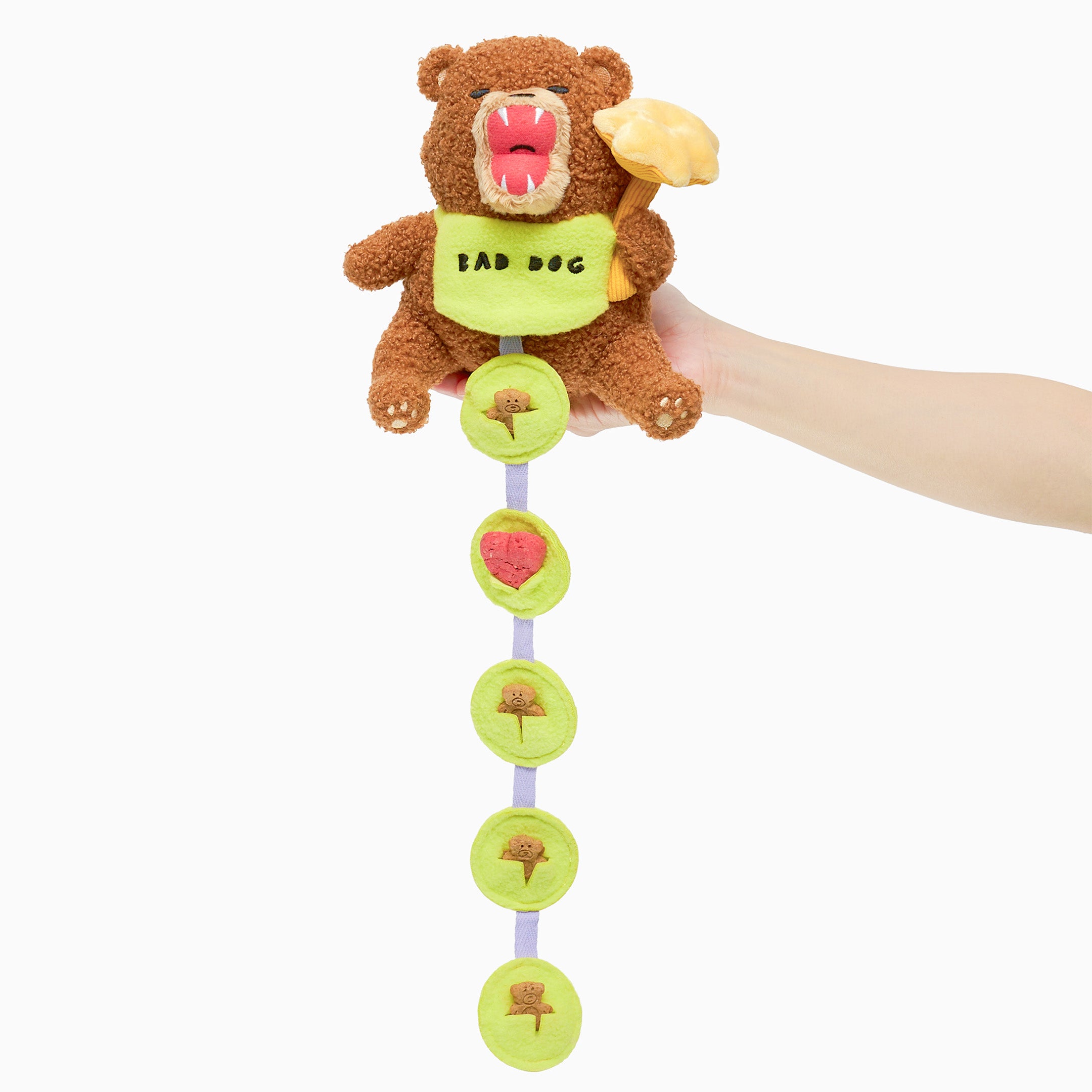 Plush toy with a bear design and colorful buttons held by a hand on a white background