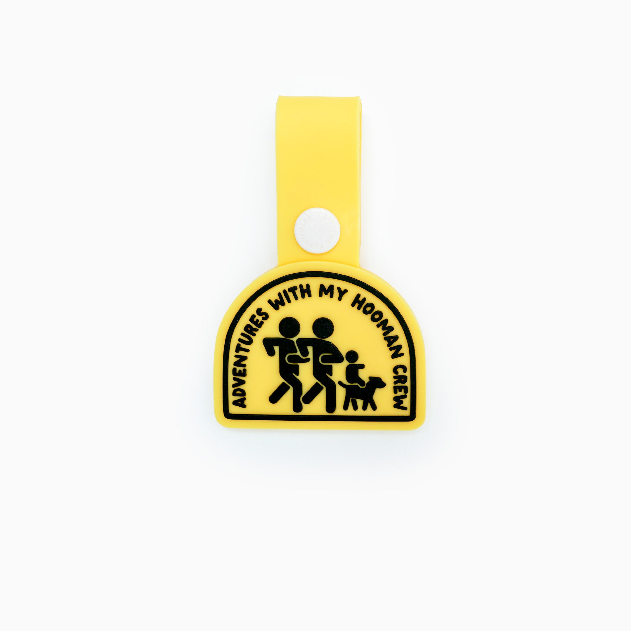 A yellow dog tag with the text ‘Adventures with My Hooman Crew’ featuring an illustration of a human family running with their dog. The tag has a loop for attaching to a collar or harness and is made of non-toxic rubber, showcasing a clean and simple design ideal for adventurous dogs and their owners.