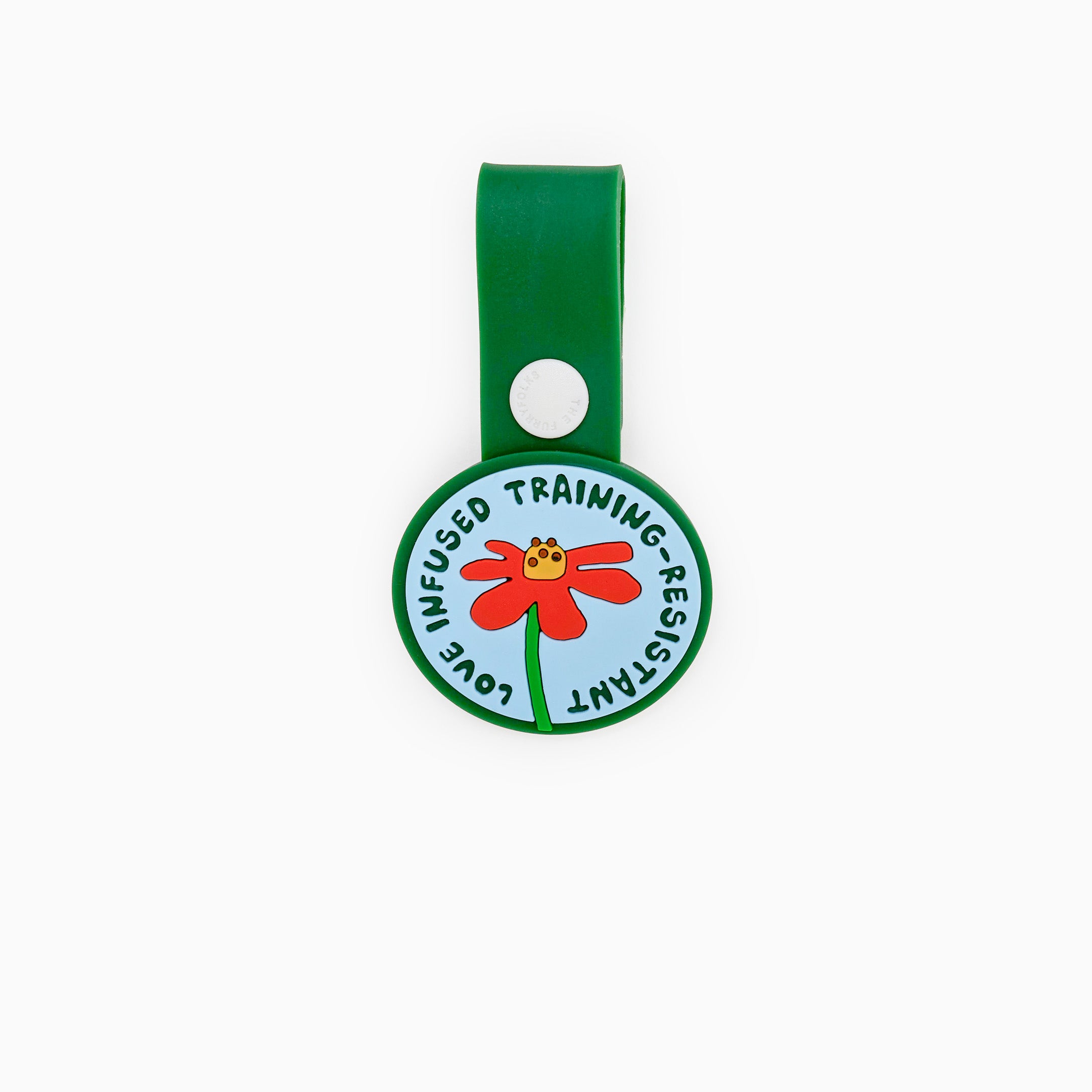 Colorful dog tag with a red flower featuring the phrase ‘Love Infused Training-Resistant.’ Attached to a green strap with a white button, this whimsical tag from The Furryfolks’ Daily Clip product line is made from 100% non-toxic rubber and is perfect for dog leashes or collars.